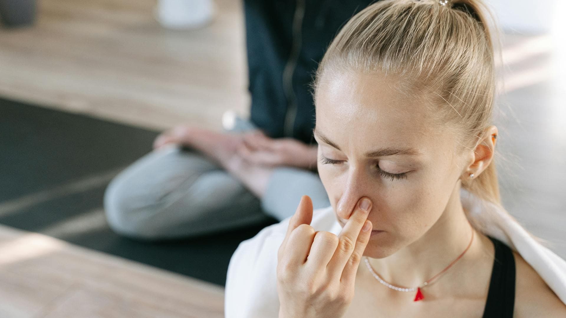 Woman practicing breathwork meditation indoors with eyes closed and focused concentration, demonstrating stress-reduction breathing techniques