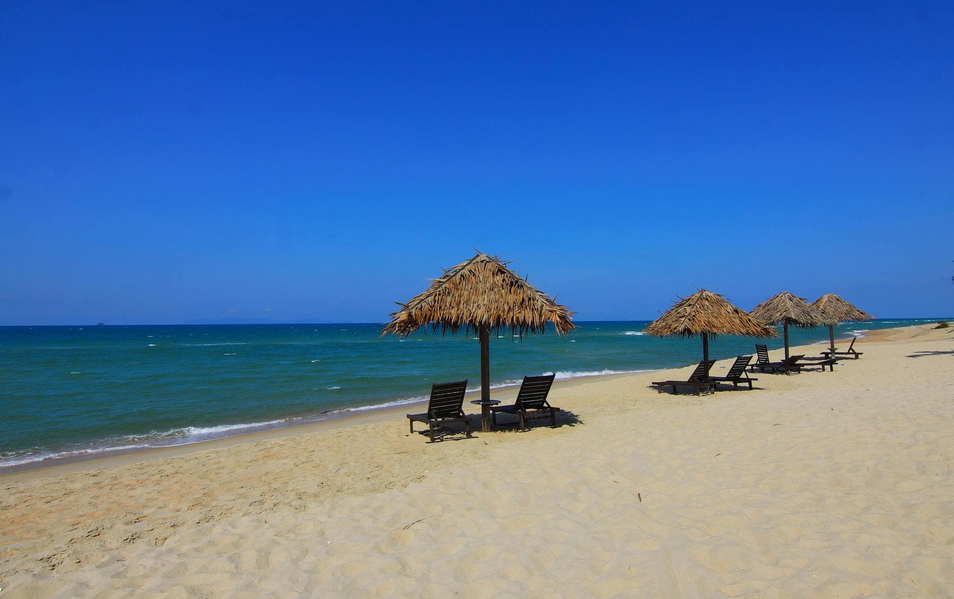 Empty stretch of white sand and calm sea at Bãi Hà My in Điện Bàn, 8 km north of An Bàng — one of Quảng Nam's quietest beaches, covered in Báo Quảng Nam's summer travel inventory.