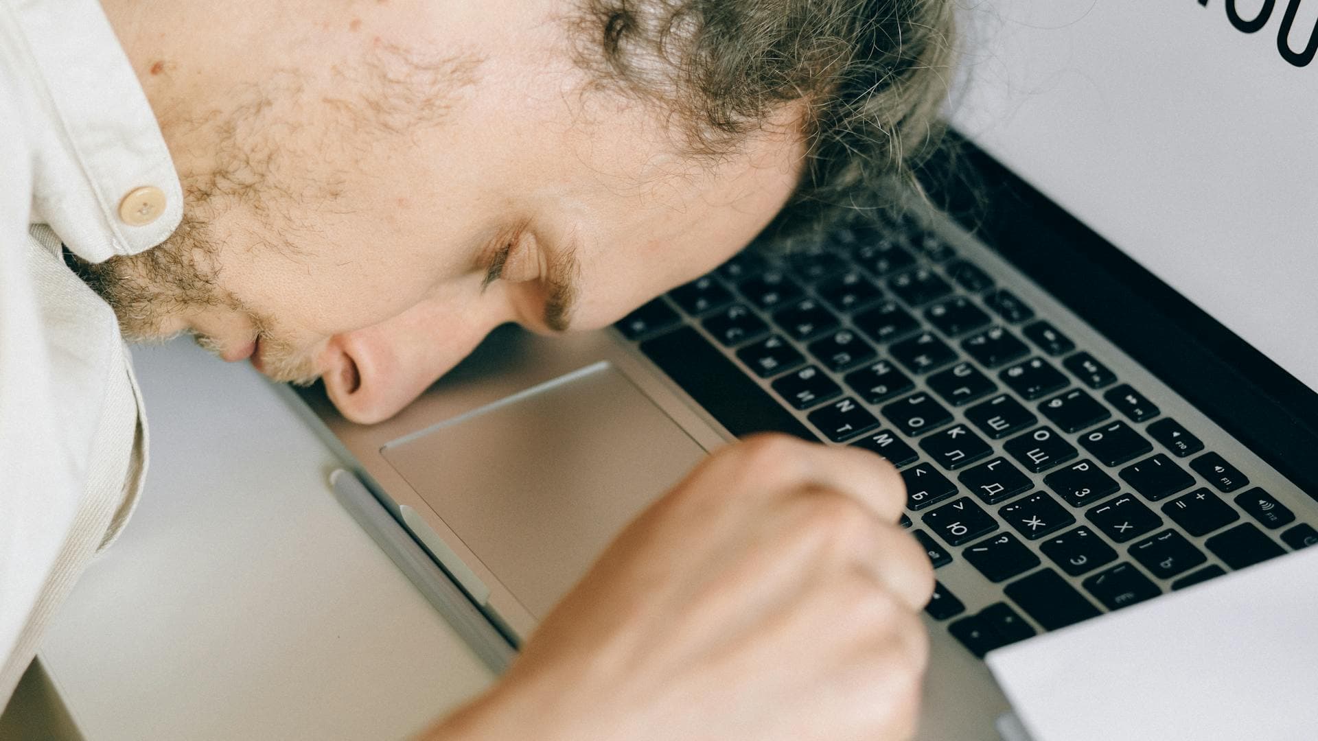 Exhausted person resting their head on a laptop keyboard, illustrating the cognitive and physical effects of accumulated sleep debt