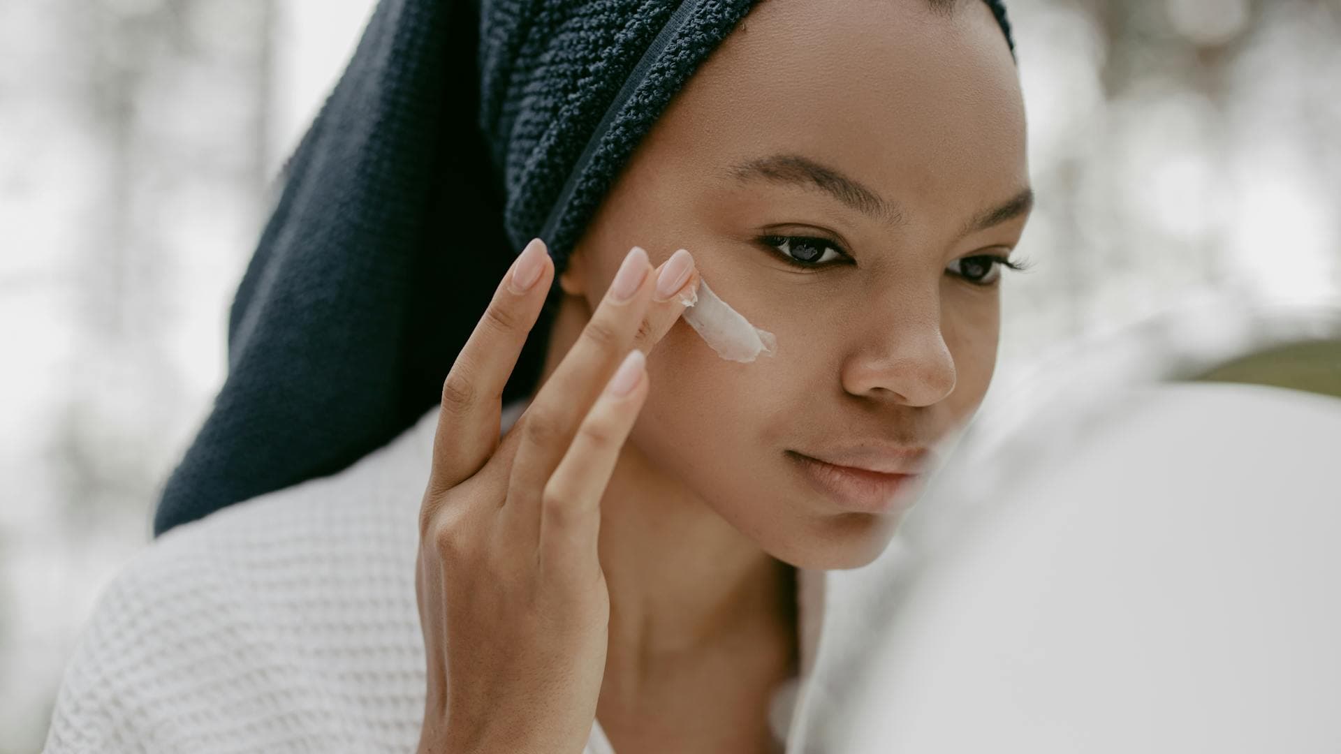 Woman gently applying facial cream as part of a nighttime skincare routine, highlighting the connection between sleep and skin health