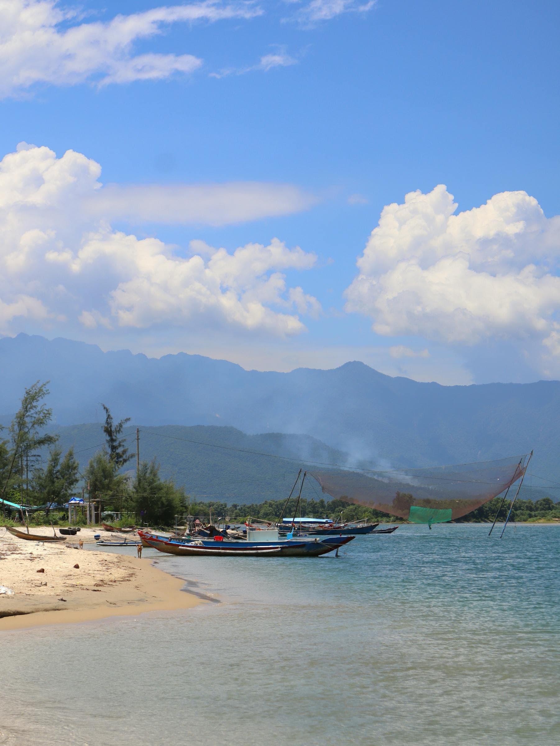 Wooden fishing boats and traditional bamboo lift nets on the shore at An Bàng beach, Hội An, Vietnam — the coastal fishing village turned beach destination 4 km east of the Ancient Town