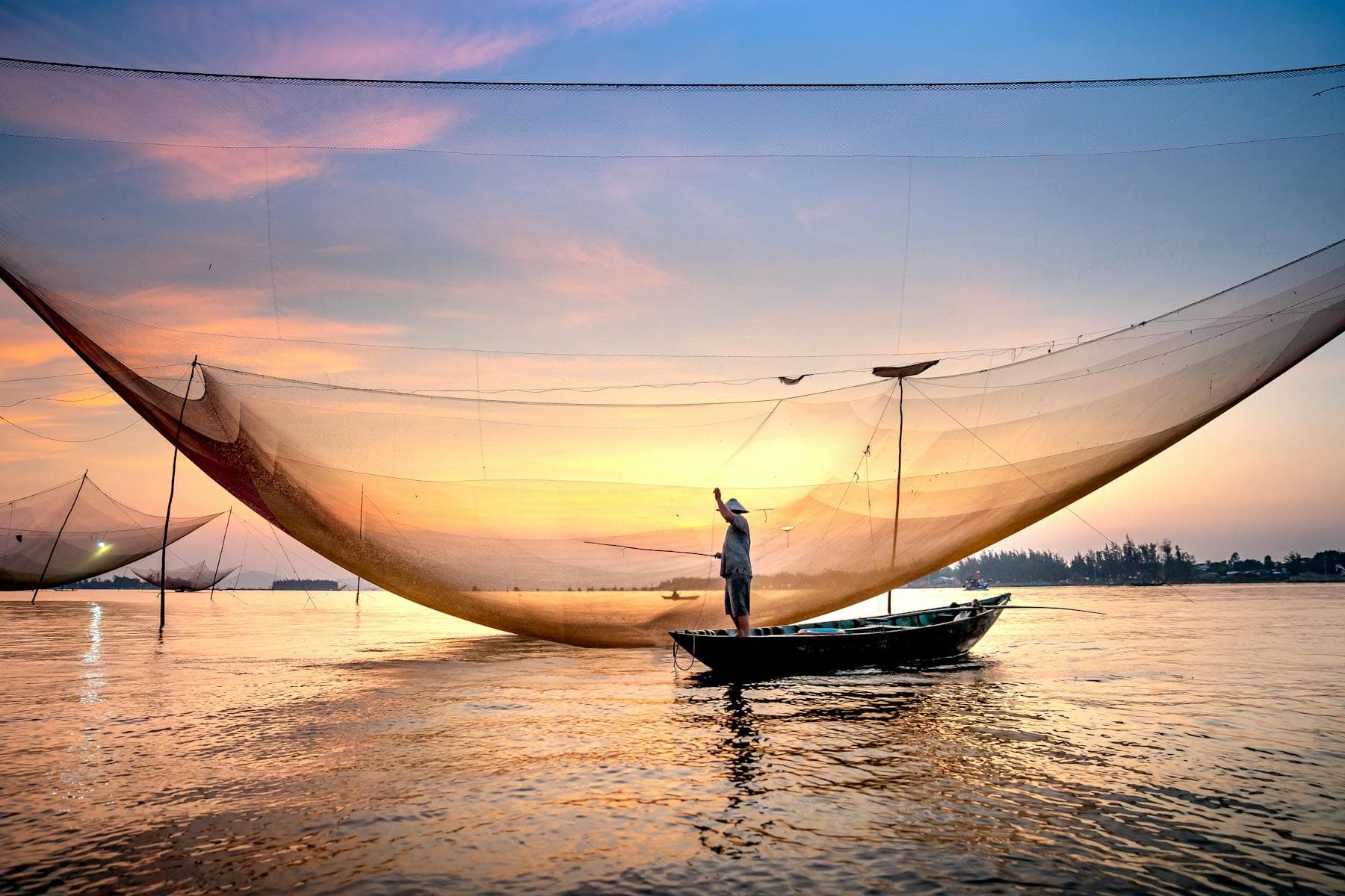 Thu Bồn River at sunset in Hội An, Vietnam — riverside view from the Cẩm Nam south bank, the quiet stretch favoured by riverside hotels