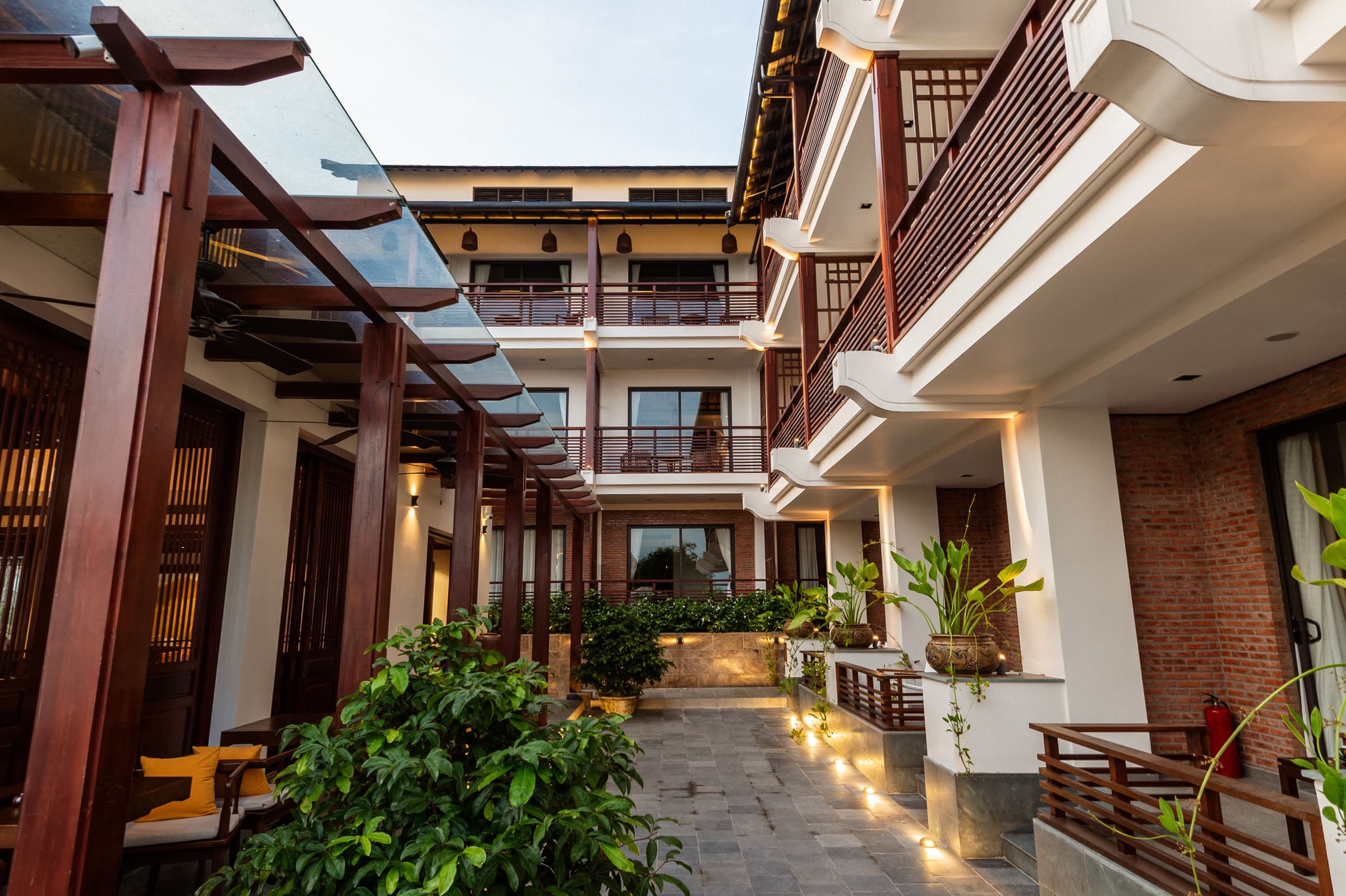 The lit courtyard walkway at Nghê Prana at dusk, the hour guests set out for the Ancient Town