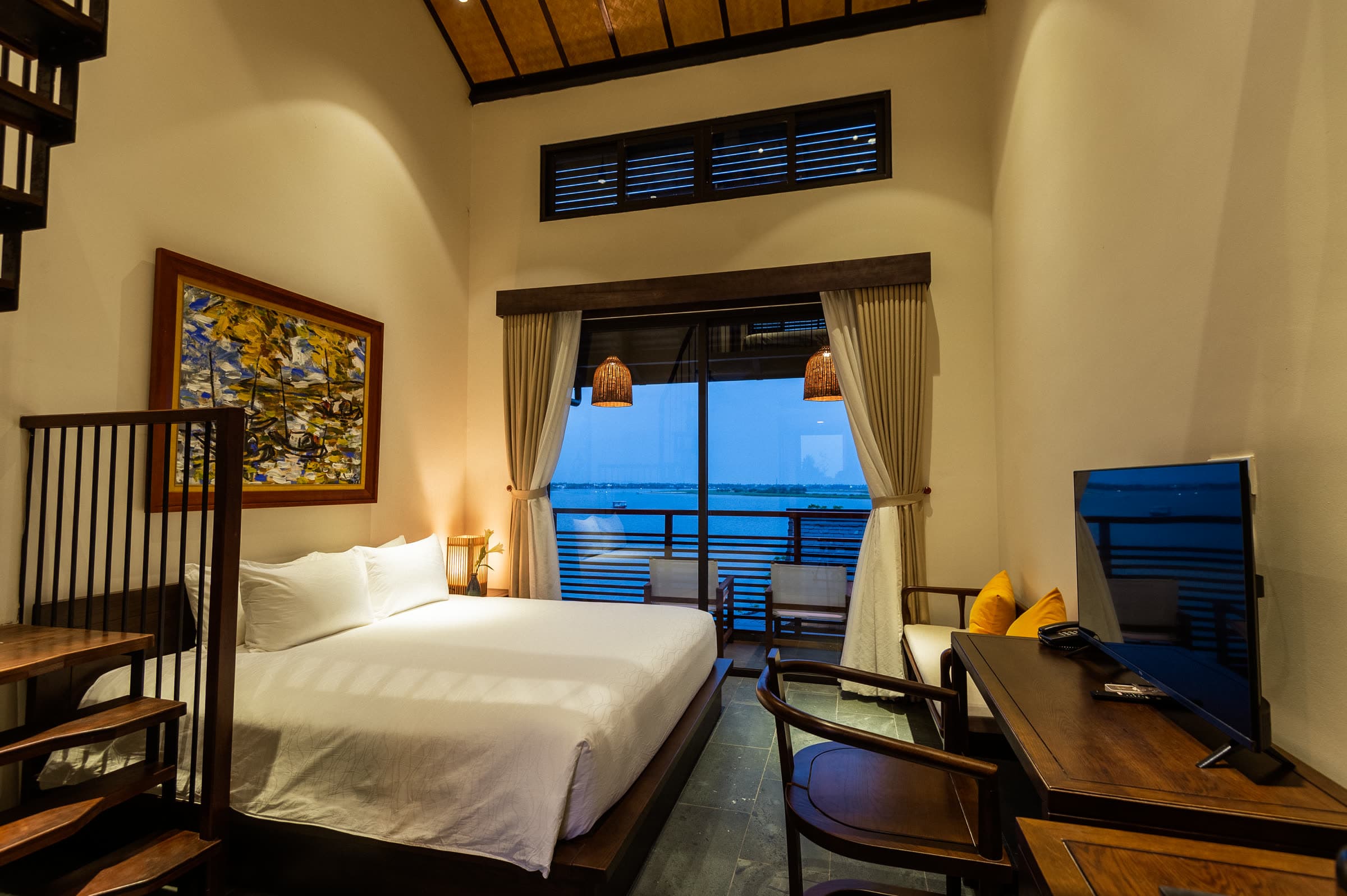 Lower-level bed of the Family Duplex with the Thu Bồn River through the balcony doors