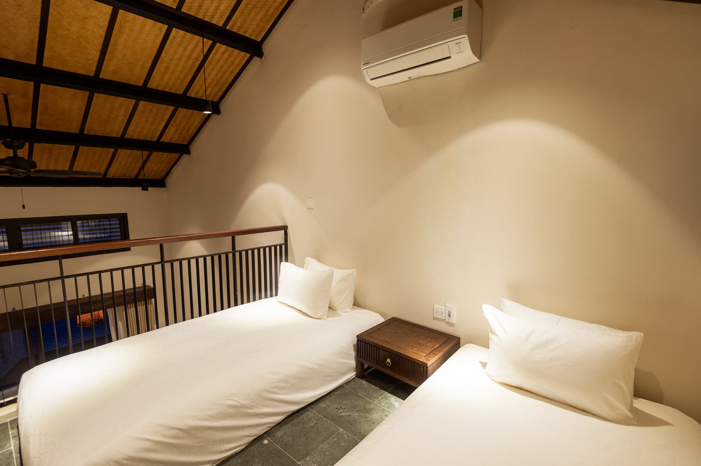 Mezzanine twin beds of the Family Duplex, with the balustrade overlooking the room below