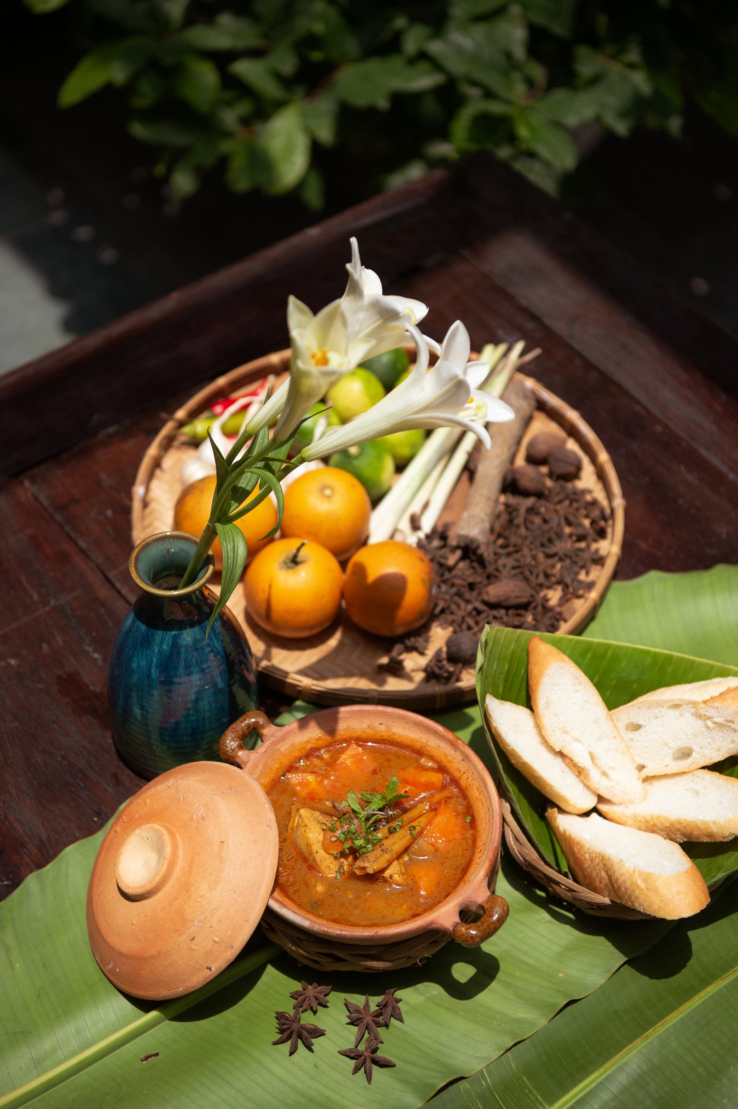 Clay-pot curry served with baguette and fresh herbs at Nghê Prana, a riverside restaurant in Hội An