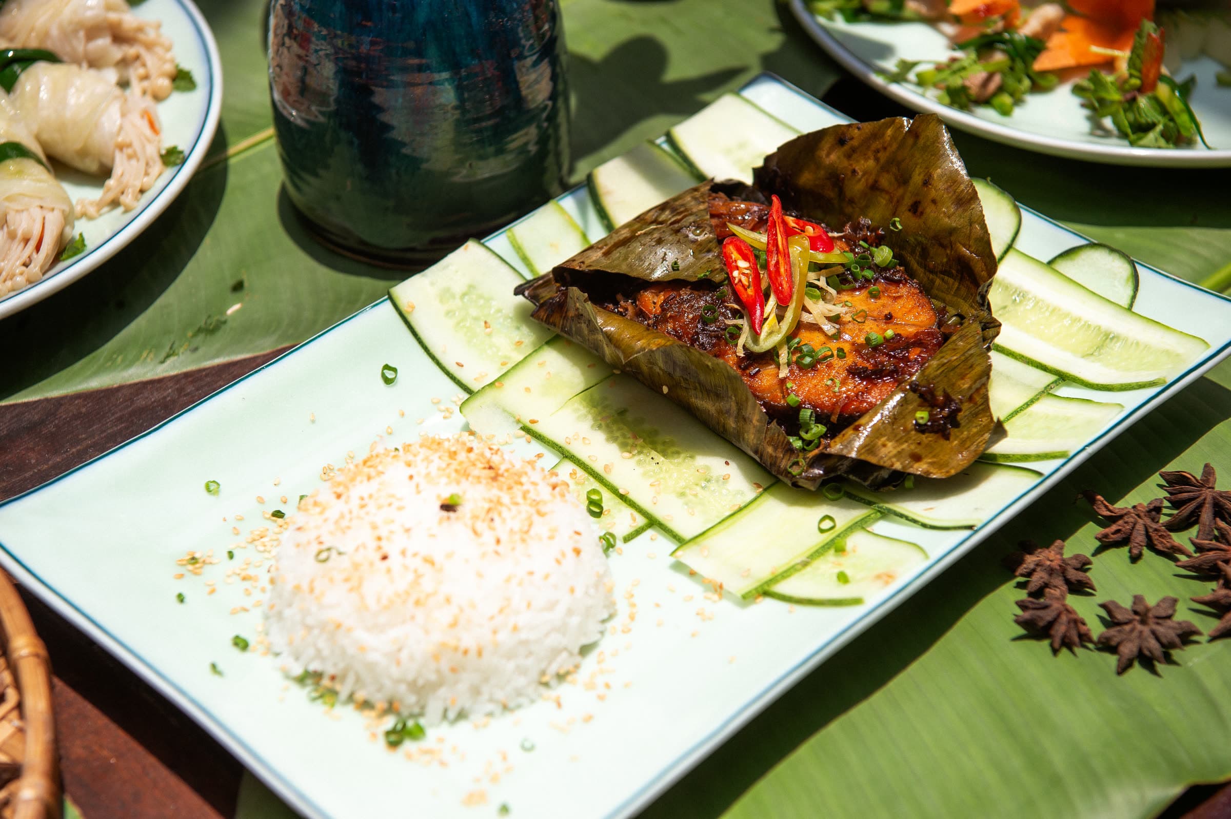 Fish grilled in banana leaf with rice and fresh herbs, served on a banana leaf at Nghê Prana, Hội An