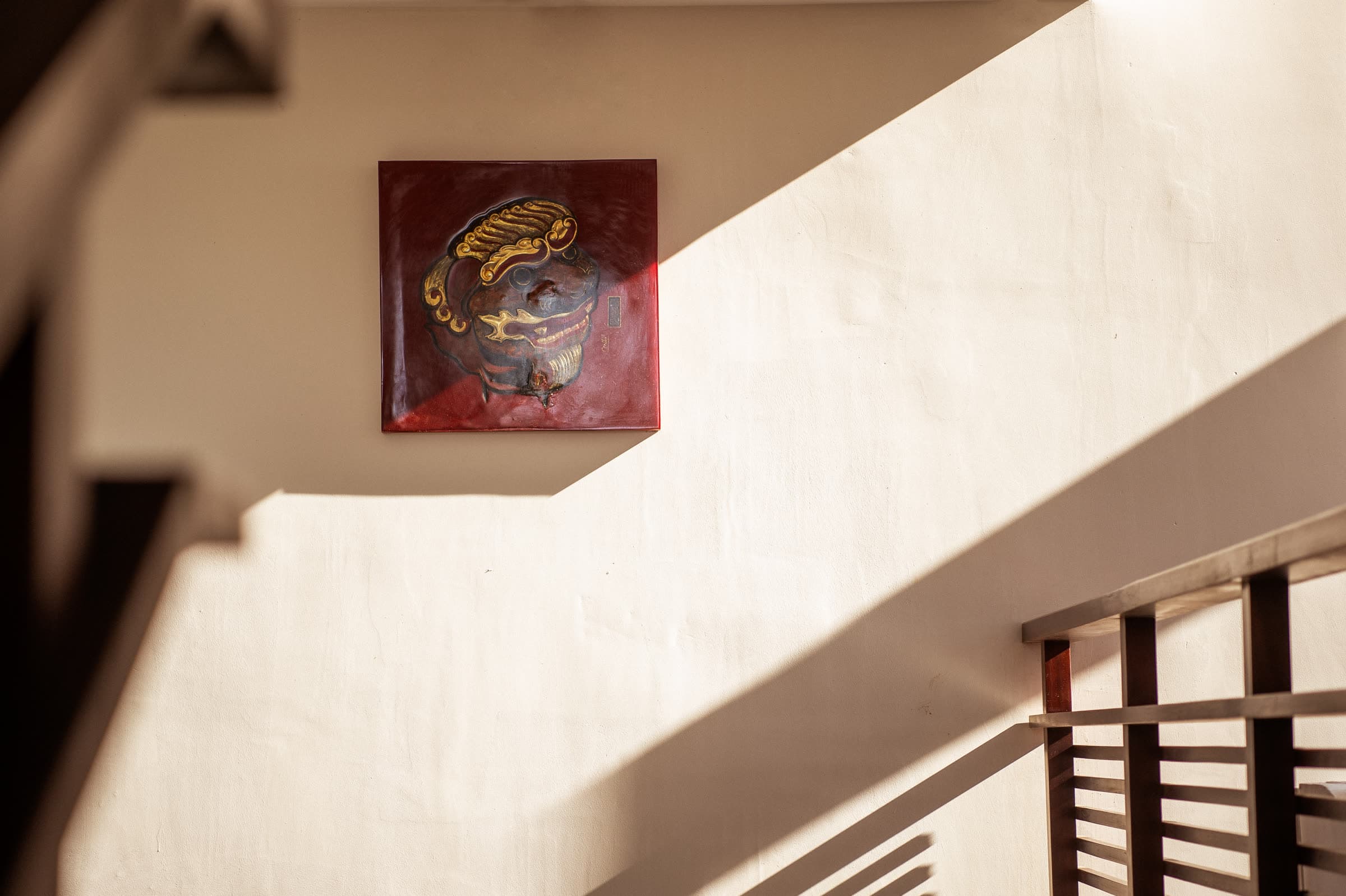 The lacquered red Nghê plaque on the stairwell wall at Nghê Prana, Hội An