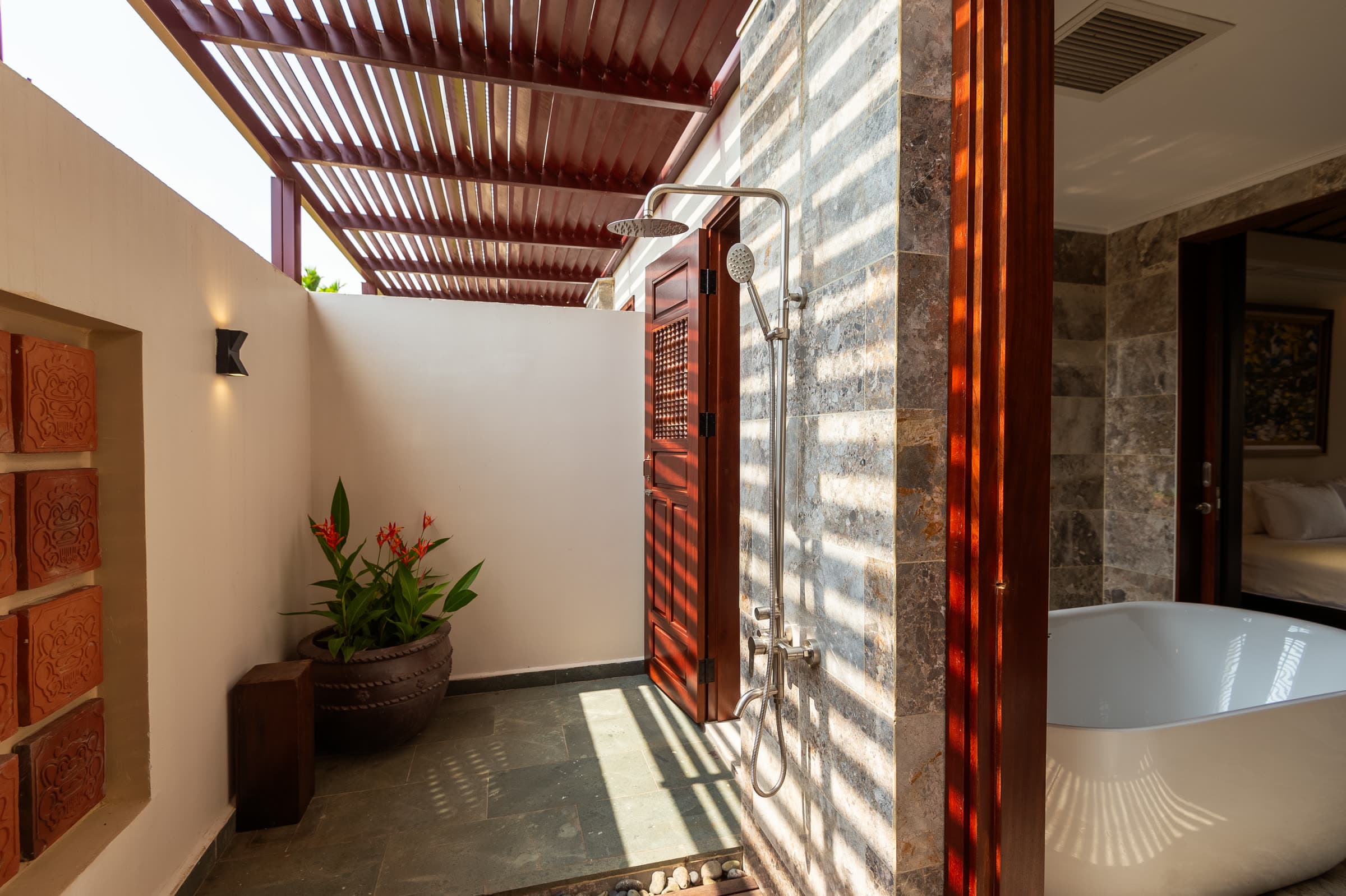 Outdoor shower courtyard of the Junior Suite, with the indoor bathtub beyond the timber doors