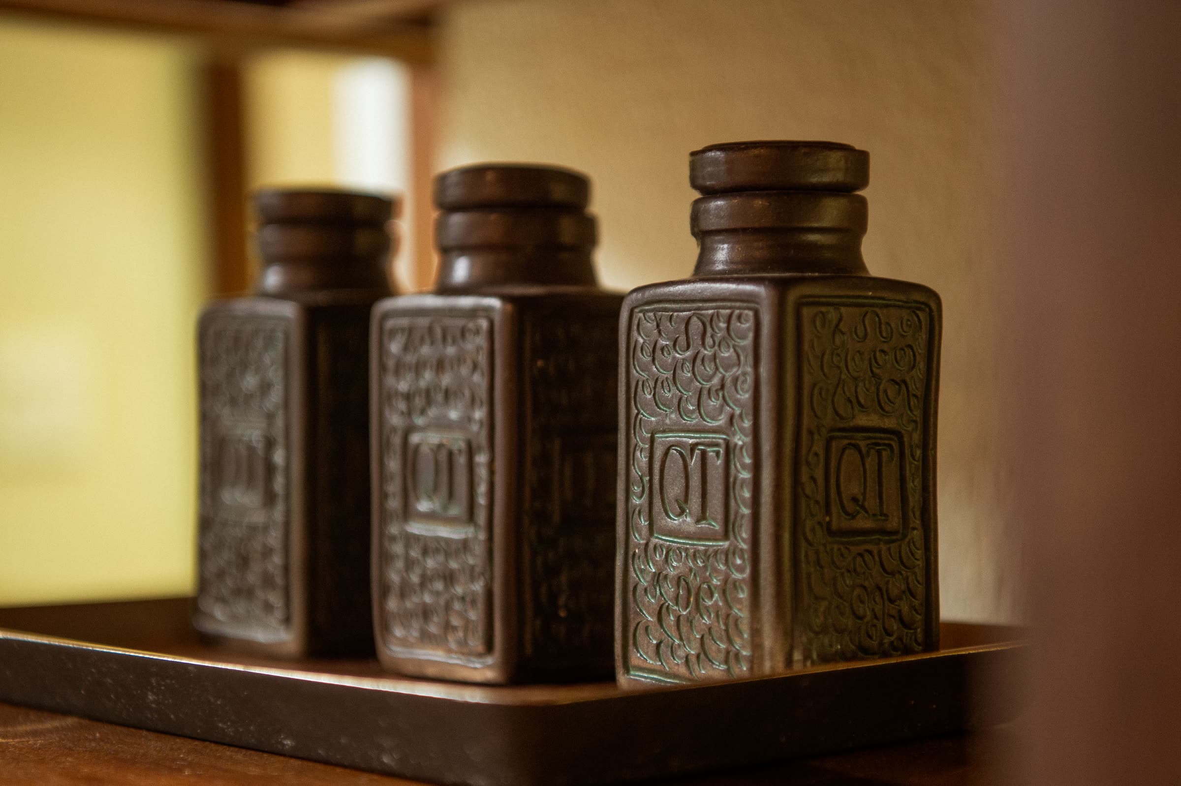 Embossed ceramic oil bottles on a brass tray in the treatment room at Nghê Prana spa