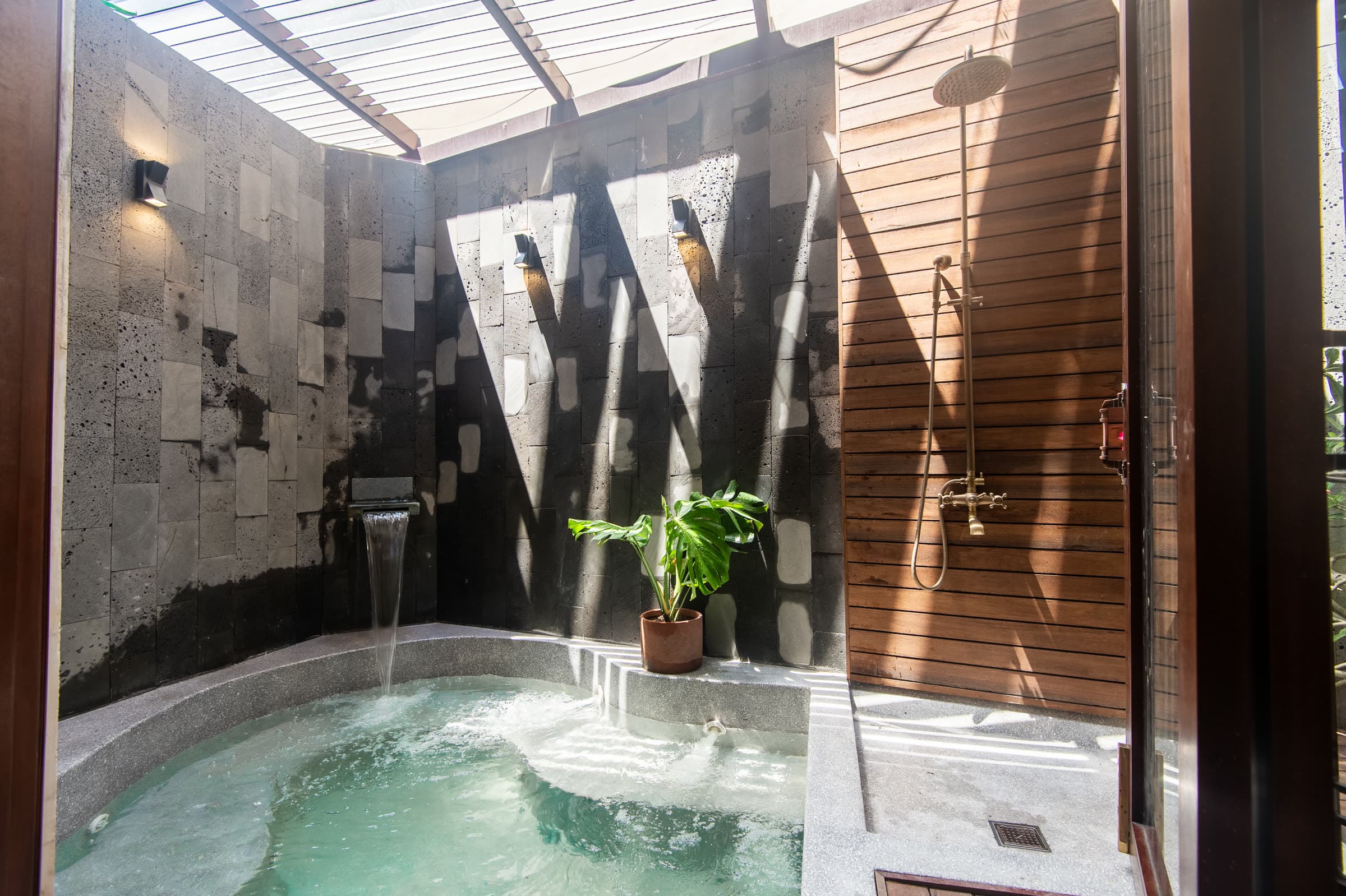 The open-air soaking pool and rain showers in the stone courtyard at Nghê Prana spa, Hội An