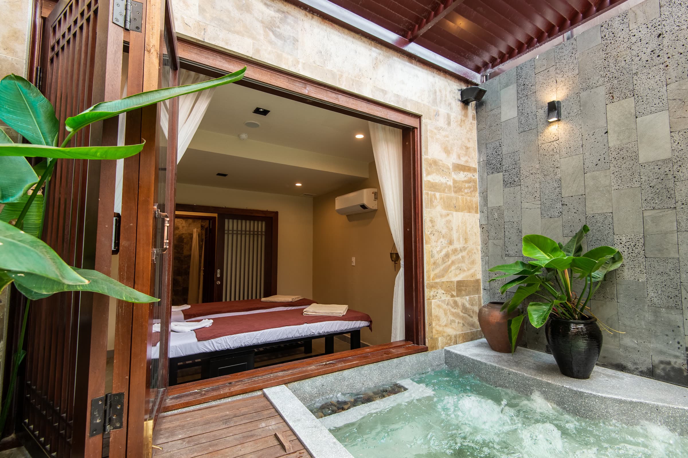 The couples treatment room at Nghê Prana with its doors folded back to a private jacuzzi courtyard, Hội An