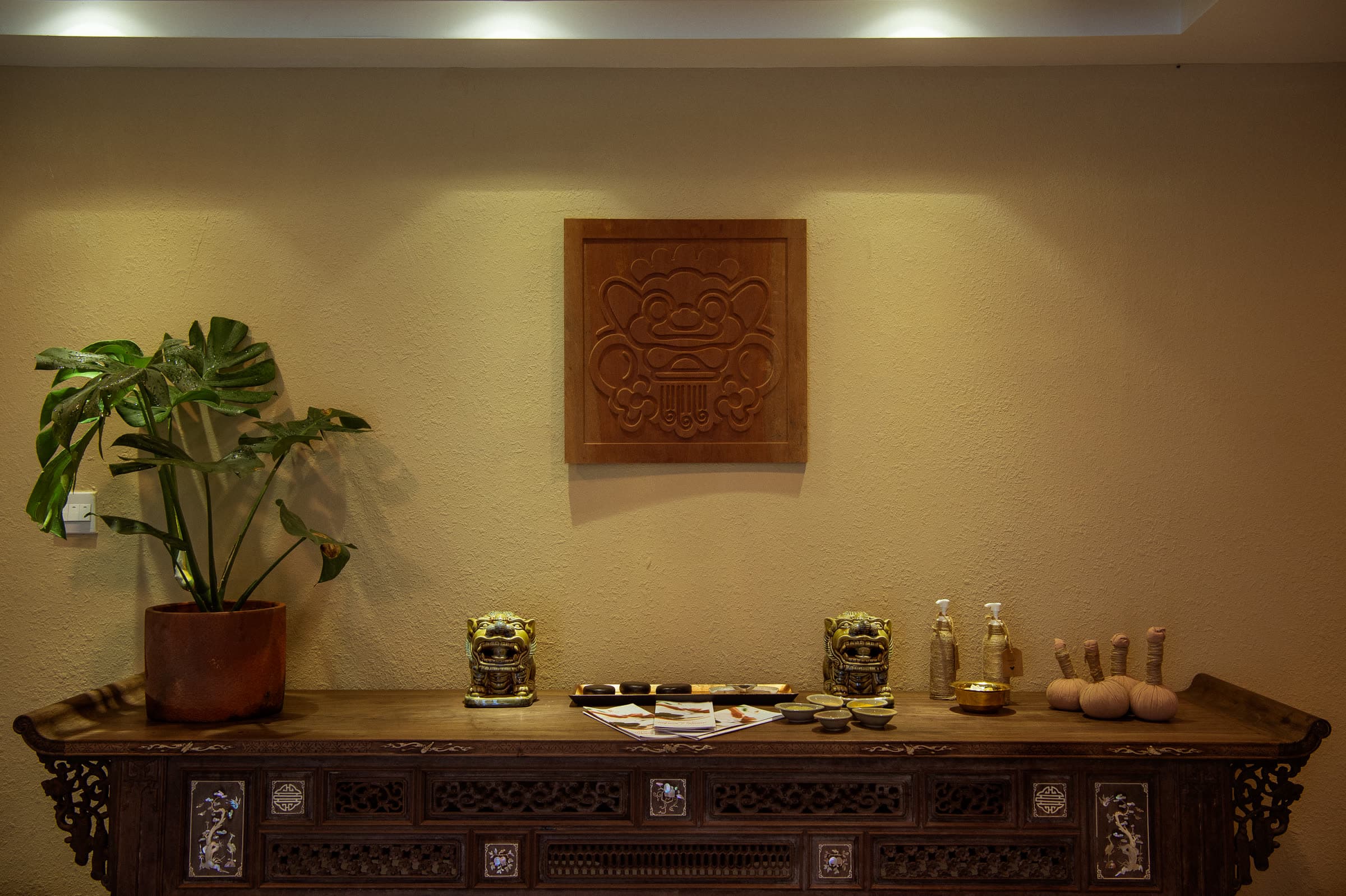 The carved timber console at Nghê Prana spa reception, beneath a wooden Nghê relief