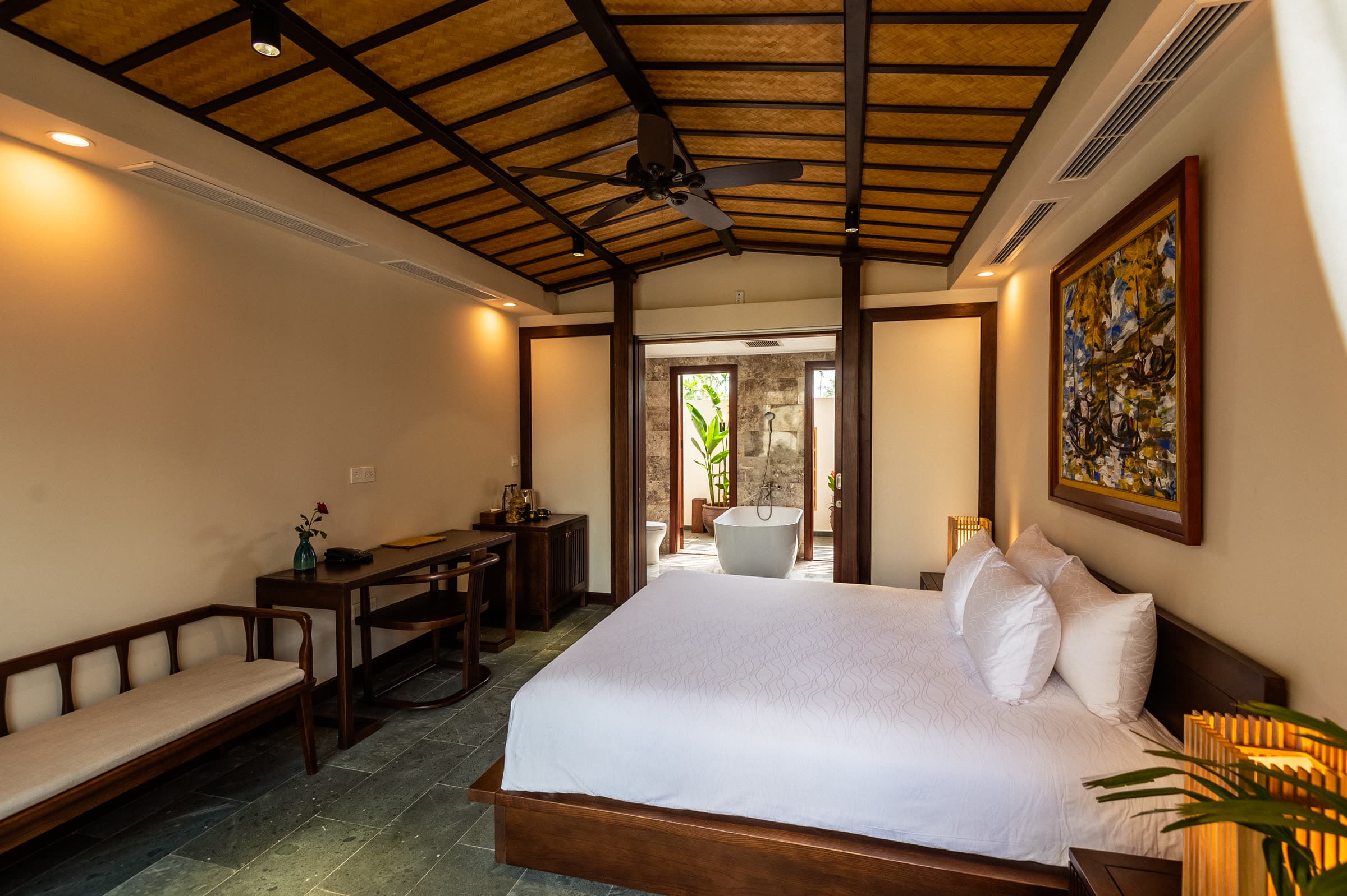 Junior Suite bedroom with a vaulted timber ceiling, ceiling fan and lacquer artwork