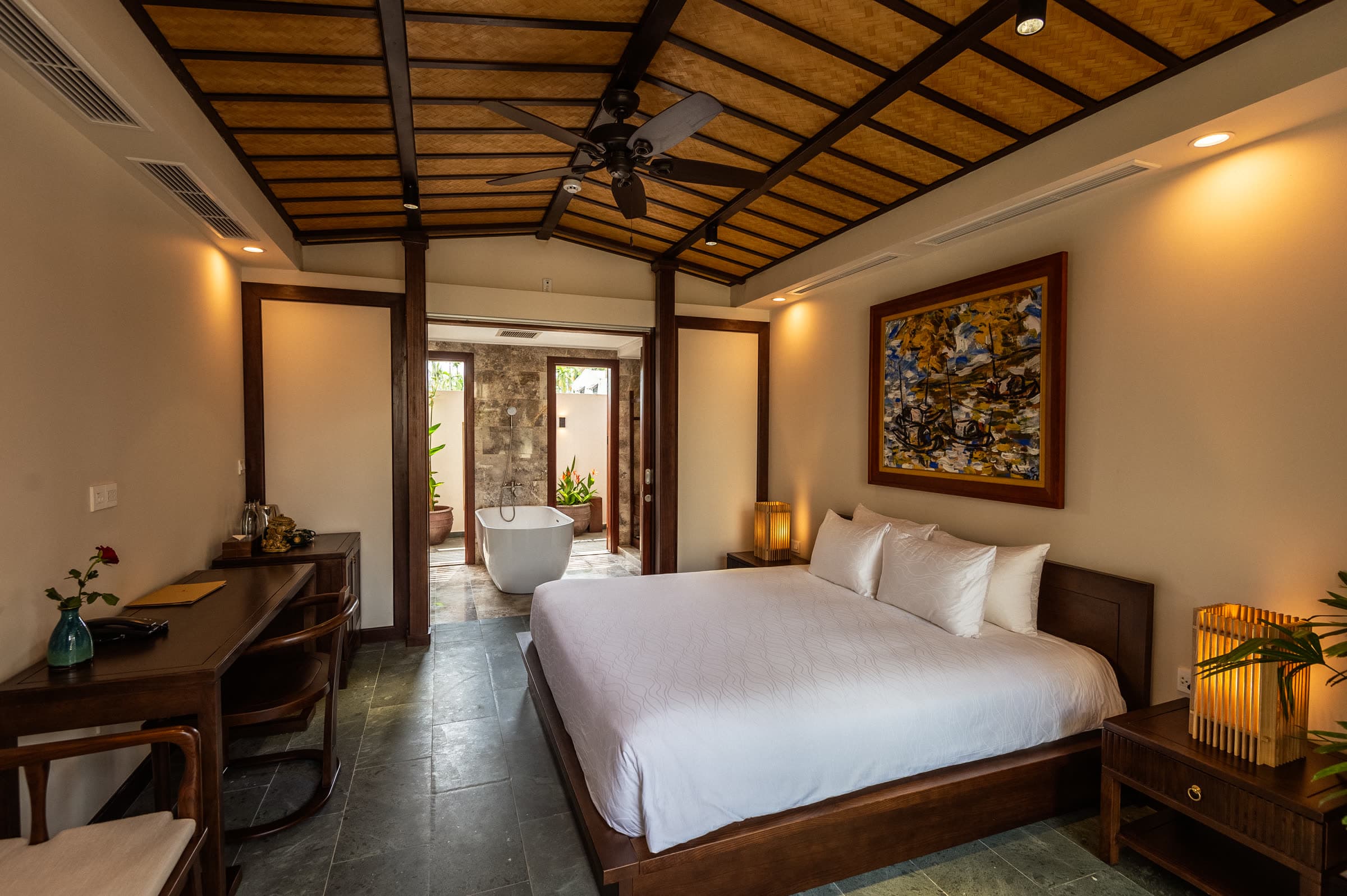 King bed under the vaulted timber ceiling of the Junior Suite, with the freestanding bathtub visible through the doorway