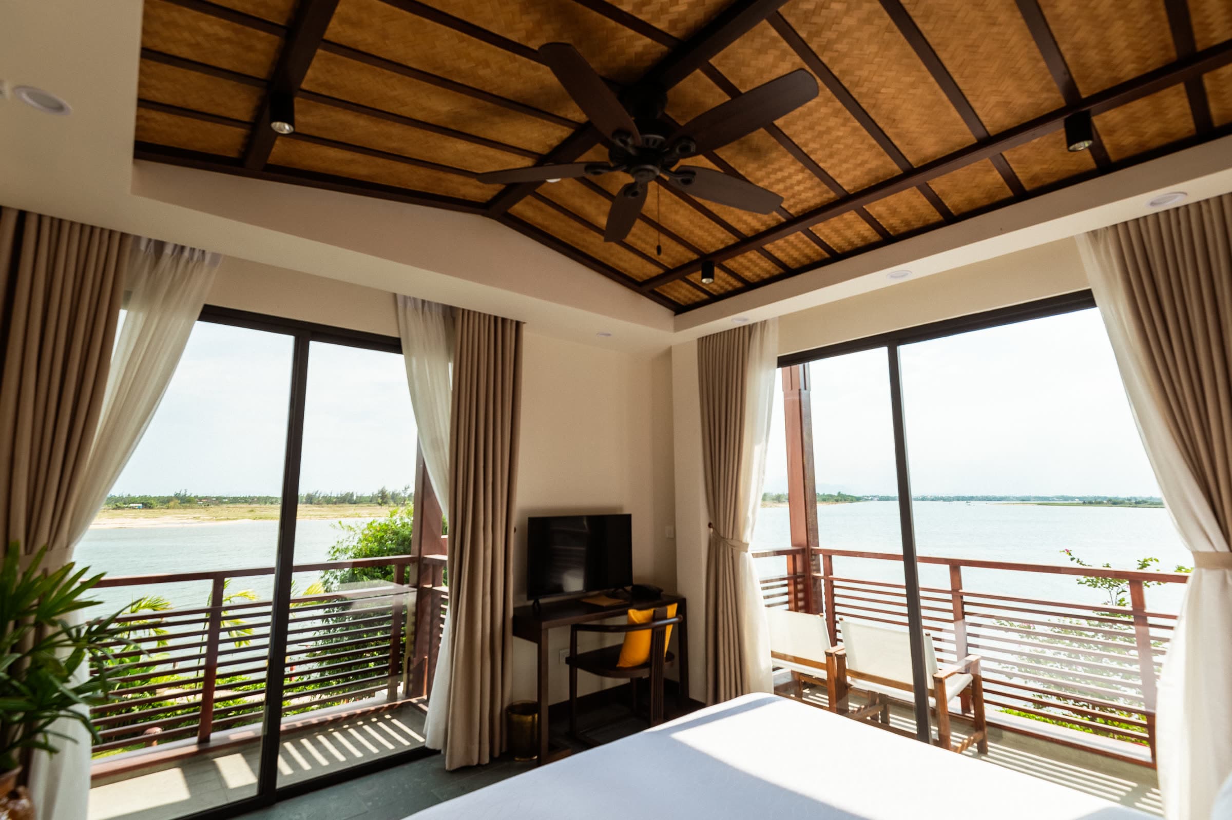 Waking to the Thu Bồn River through the open balcony doors of a riverview suite at Nghê Prana