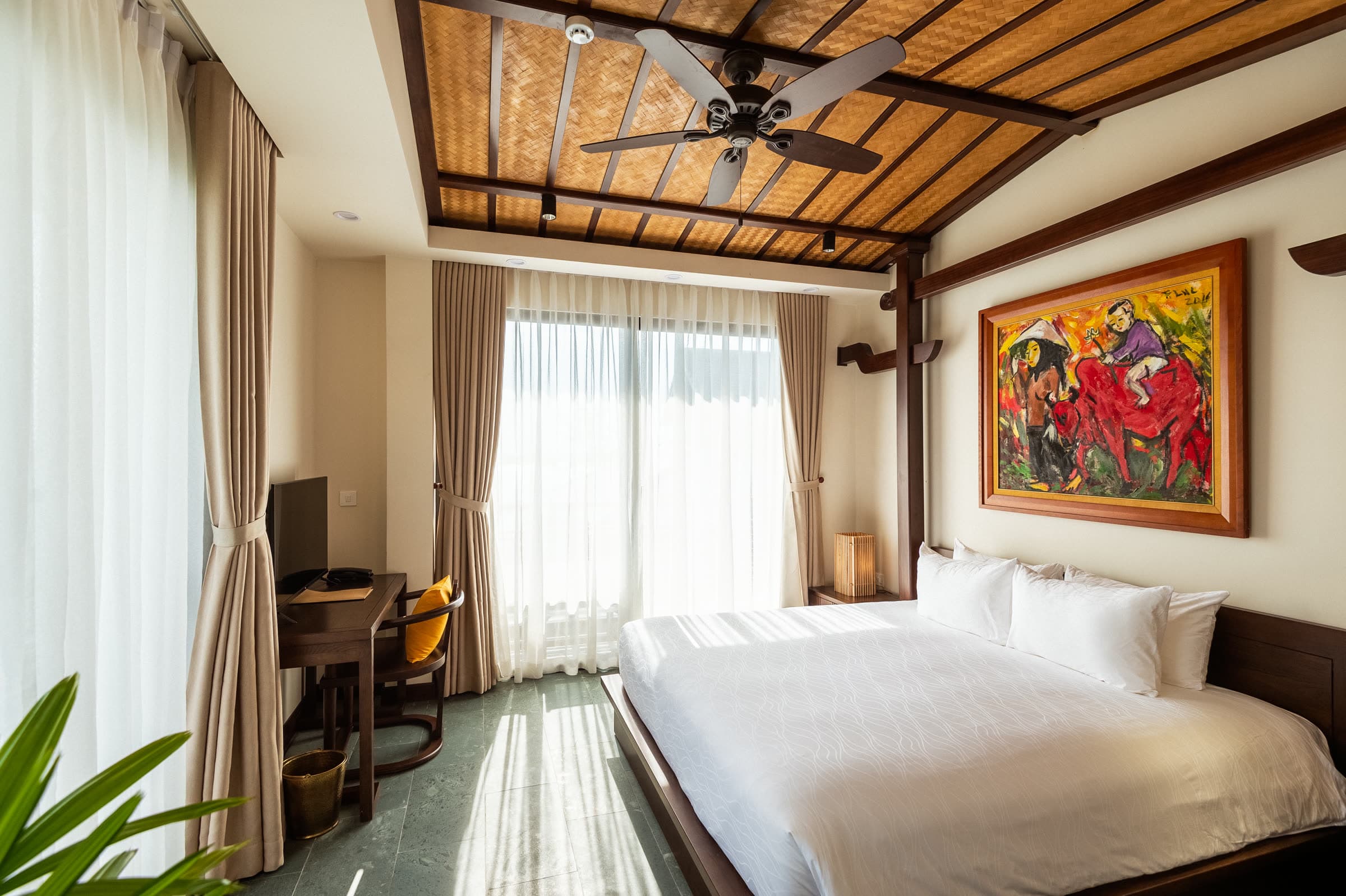 River Suite bedroom under a vaulted timber ceiling, the Thu Bồn River filling the window