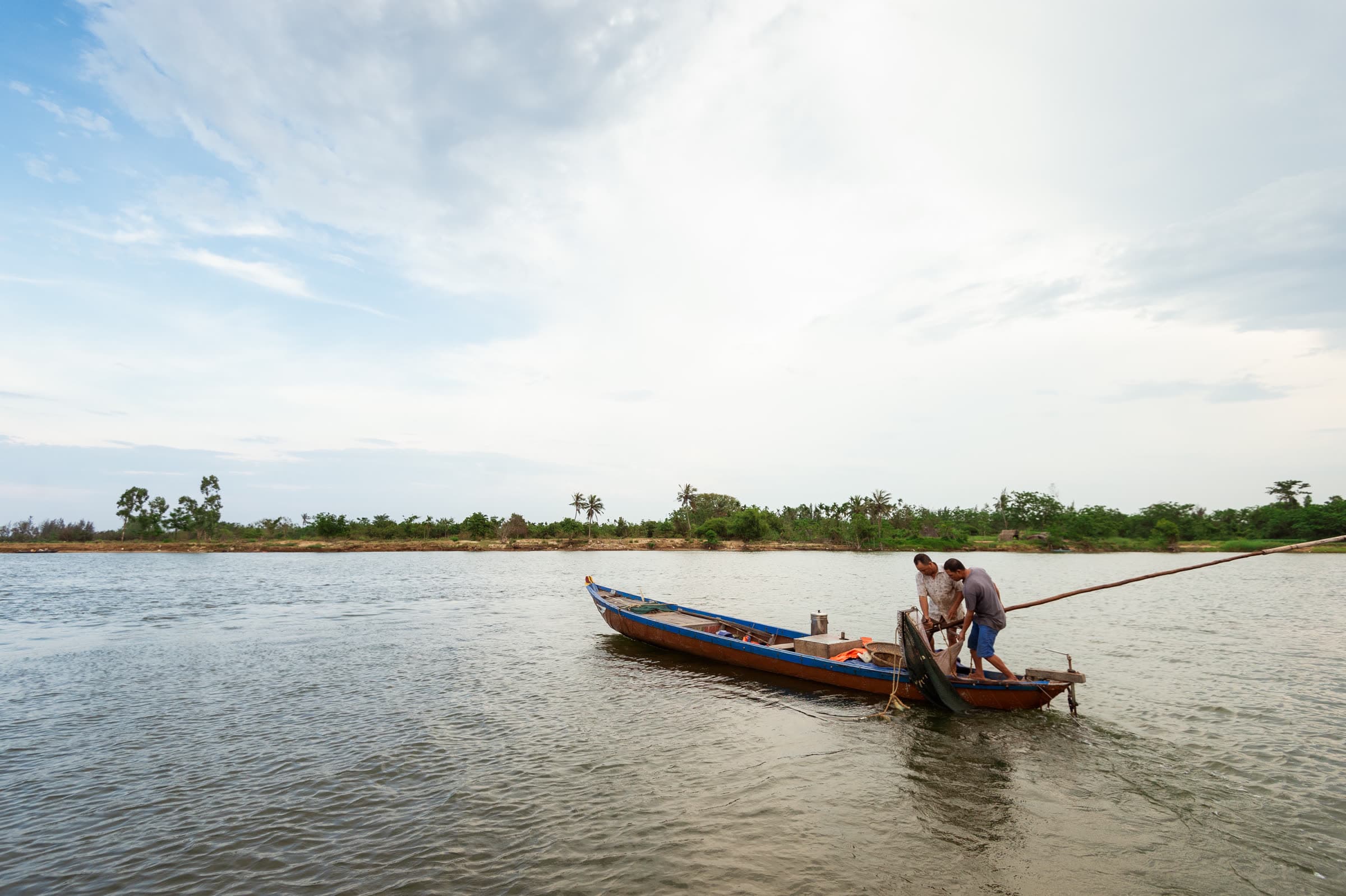 Fishermen working a net from a wooden boat on the Thu Bồn River near Hội An