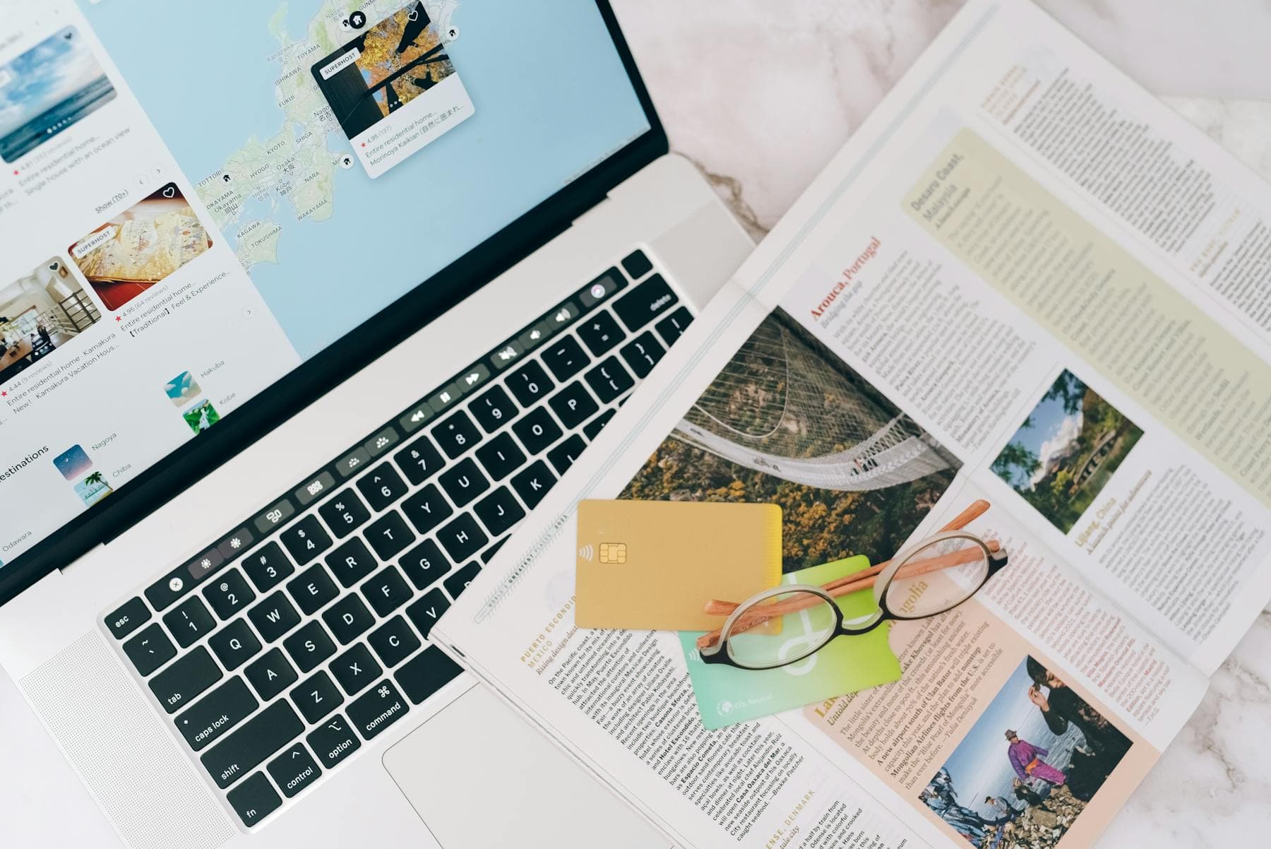Laptop showing booking site next to credit card, glasses and travel magazine — booking direct vs Booking.com for Hội An hotels and rate parity
