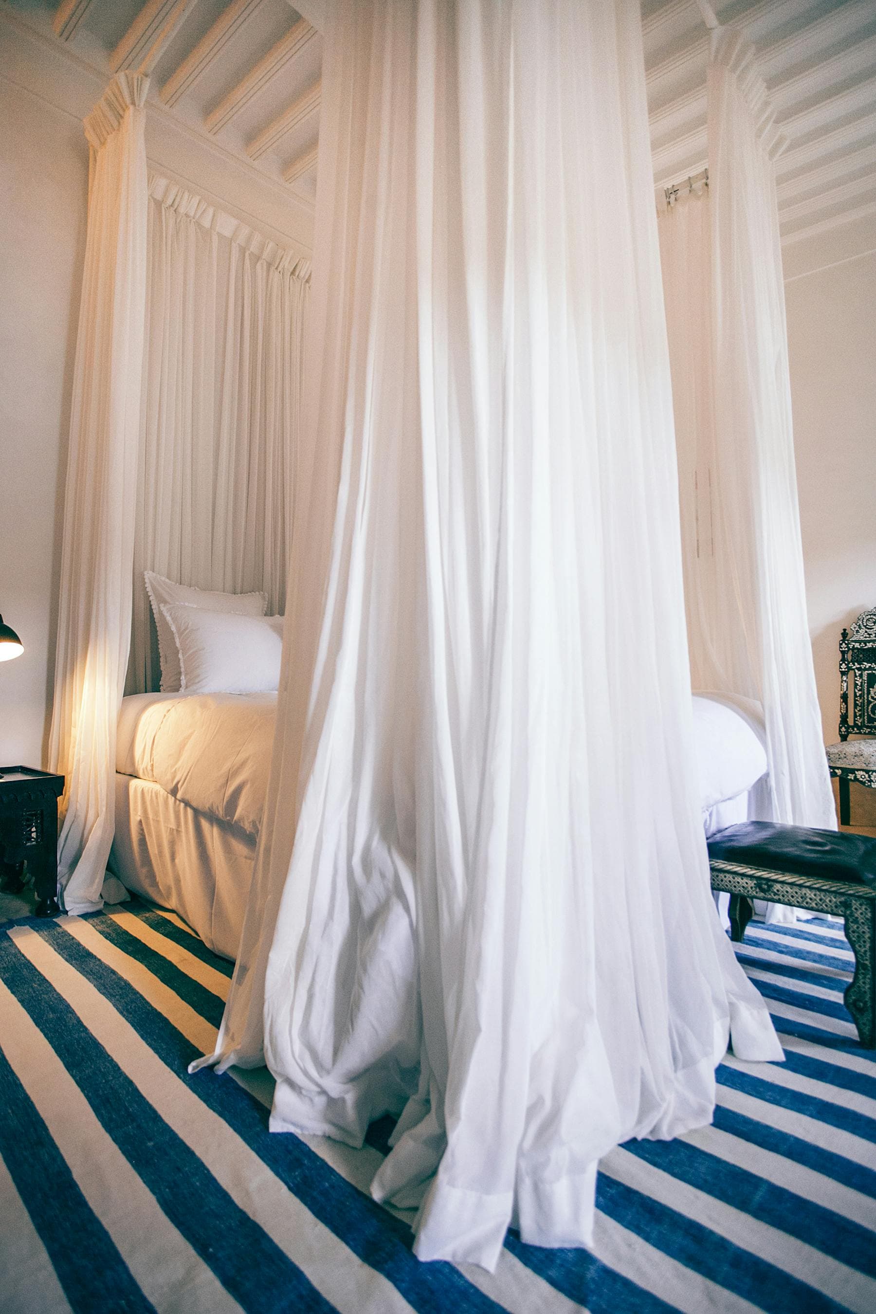 Quiet Hội An riverside hotel bedroom with four-poster canopy bed and drawn curtains for deep sleep — the riverside vs Old Town sleep difference