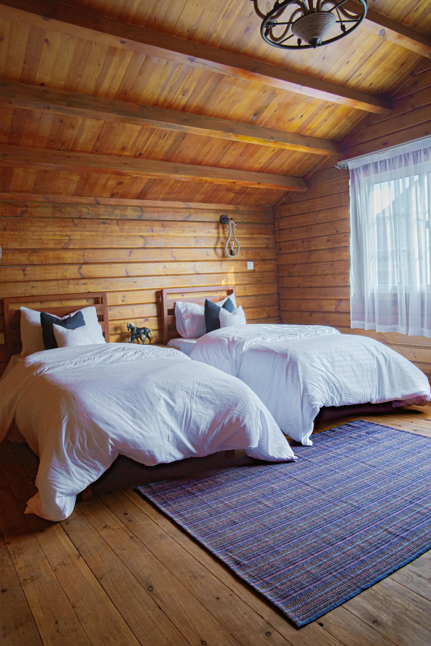 Quiet wood-panelled hotel bedroom with twin beds, white linens and morning light — one night Hoi An recovery stop between Hue and Da Nang at Nghê Prana, a Hoi An riverside hotel