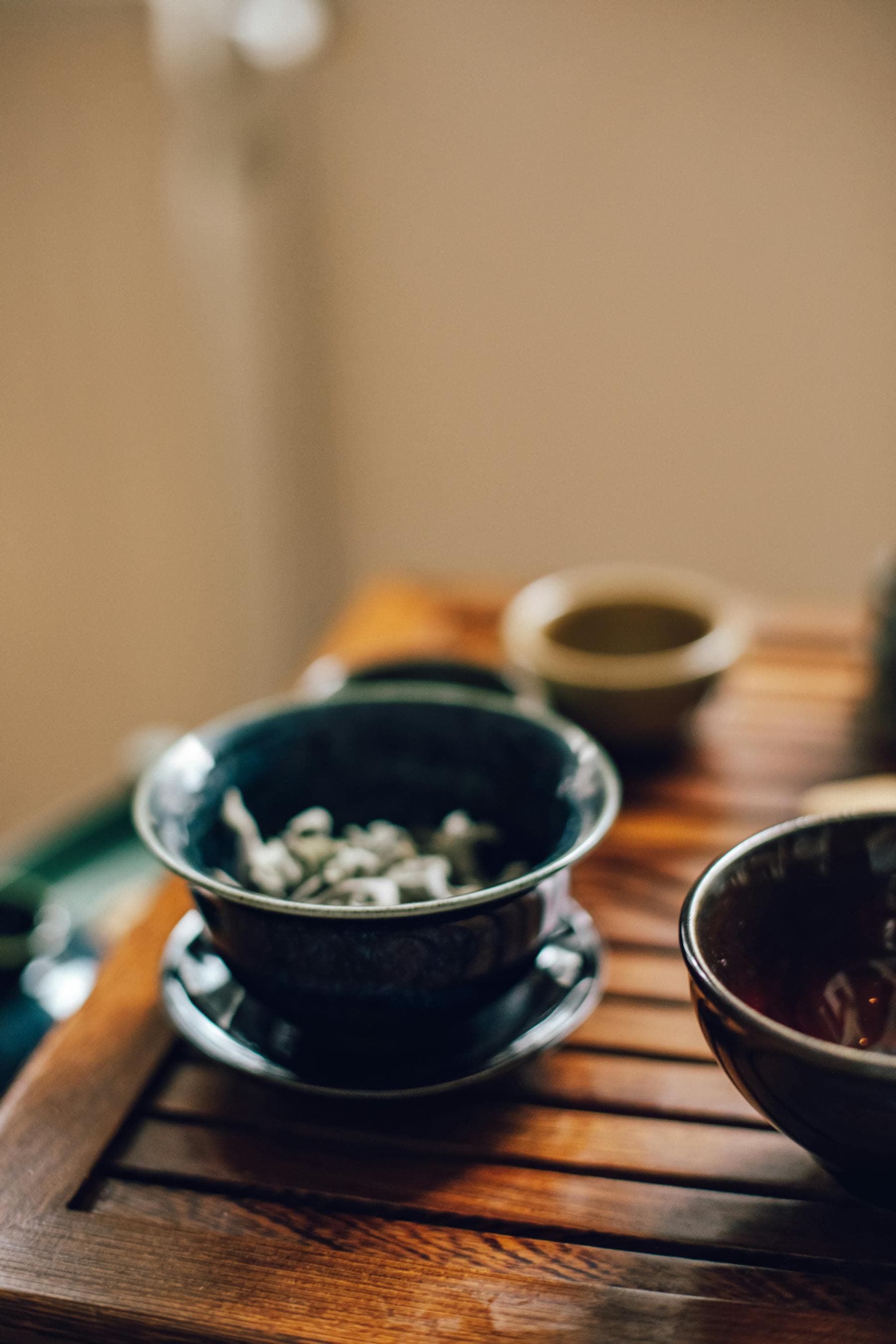 Gaiwan ceramic tea bowl with green tea leaves on a wooden tray — sober curious travel Hoi An Vietnamese tea tradition