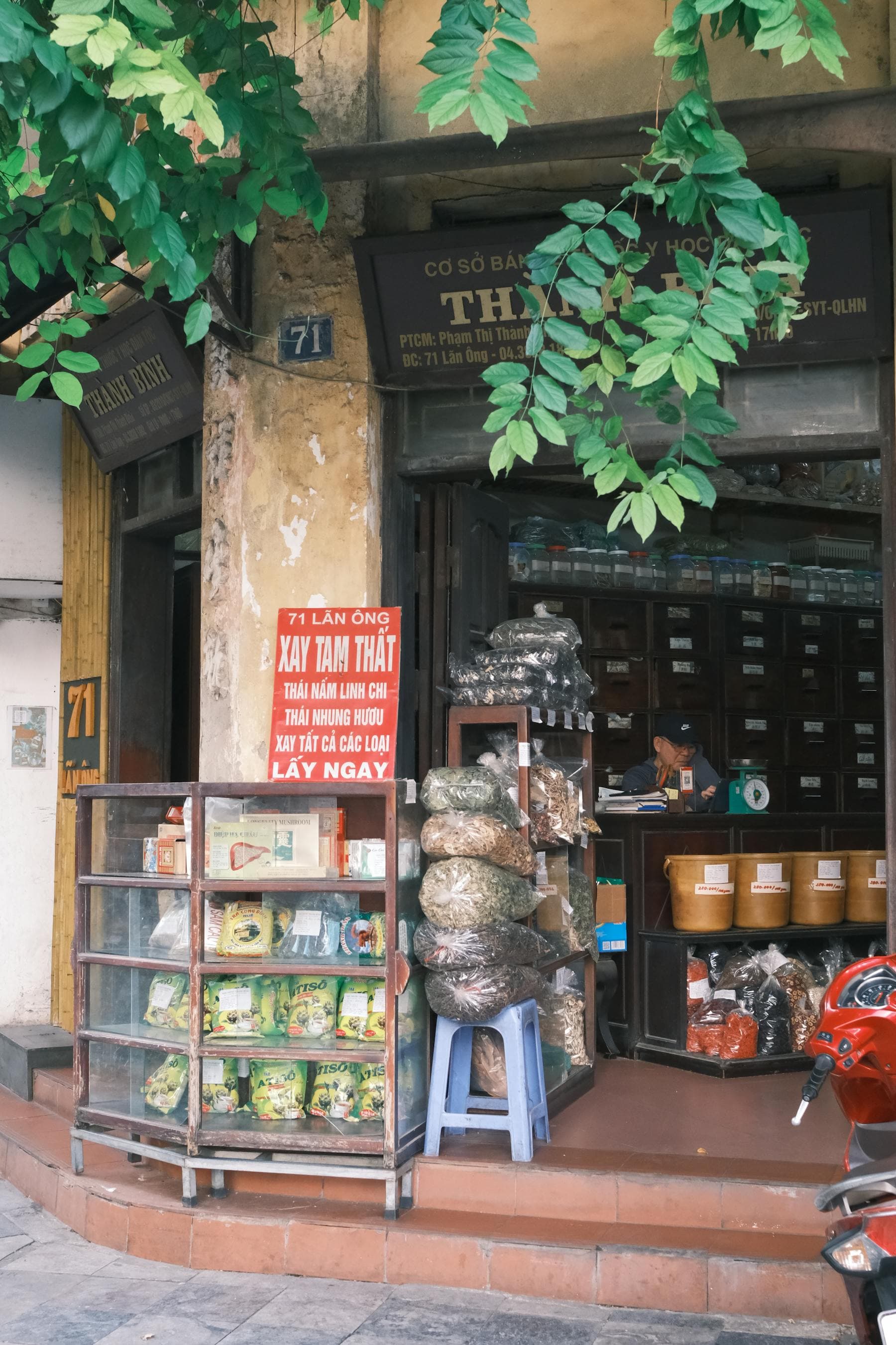 Traditional Vietnamese thuoc nam herbal medicine shop on Lan Ong Street in Hanoi with sacks of dried herbs and wooden apothecary drawers, the living pharmacological tradition that overlaps with South Indian Ayurveda in Vietnamese wellness retreats